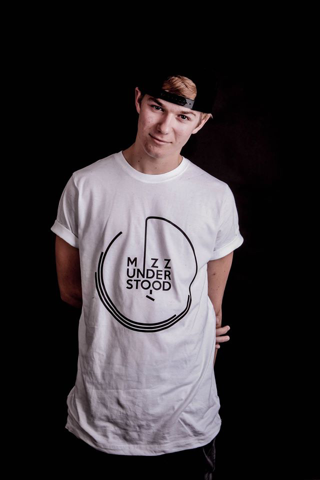 Graduate August smiling in a white T-shirt and backwards cap